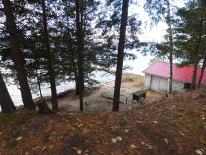 a building with a red roof in the woods at Cranberry Cottage on Torch Lake in Alden +39 photos