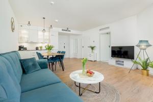 a living room with a blue couch and a table at Prestige 113 - tuż przy plaży, z widokiem na morze, parkingiem i WiFi w cenie pobytu - Easy-Rent Apartments in Pobierowo