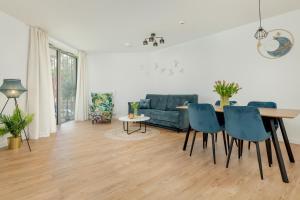 a living room with a table and blue chairs at Prestige 113 - tuż przy plaży, z widokiem na morze, parkingiem i WiFi w cenie pobytu - Easy-Rent Apartments in Pobierowo