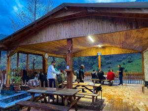 a large wooden pavilion with people sitting at tables at Kapuzbaşı Şelaleleri Uçar pansiyon in Büyükçakır
