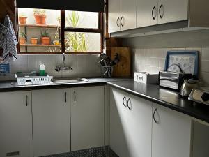 a kitchen with white cabinets and a sink at African Sun Guest House in Molen Drift