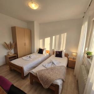 two beds in a room with two windows at Above the City, walk everywhere - 2BR, 2 Baths in Skopje