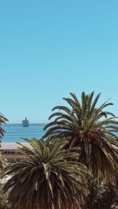 two palm trees on a beach with a ship in the water at Getaway in Valparaiso in Valparaíso