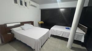 a bedroom with two beds and a pole at SR Hotel e Pousada Pirambu in Pirambu