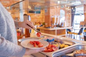 a person holding a plate of fruit with a knife at Logis Mar I Sol - Hôtel Restaurant en bord de Mer in Saint-Cyprien +82 photos