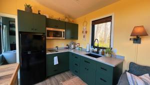 a kitchen with green cabinets and a black refrigerator at Bison Farm - Cabin "Vista" in Culpeper +20 photos