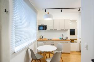 a kitchen with white cabinets and a table and chairs at Apartamenty Mazurska Strefa in Pisz