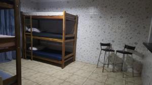 a room with a bunk bed and two bar stools at Refúgio Beira-Mar in Itanhaém