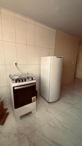 a kitchen with a stove and a white refrigerator at Quarto Triplo in Areia
