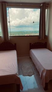 two beds in a room with a large window at Quarto Triplo in Areia
