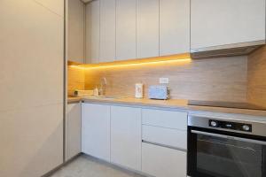 a kitchen with white cabinets and a sink and a stove at Premium Rent Podgorica in Podgorica