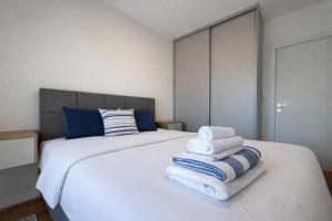 a bedroom with a white bed with blue pillows and towels at Premium Rent Podgorica in Podgorica