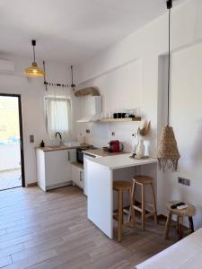 a white kitchen with a counter and stools at Kanal Vstay #2 in Kithnos