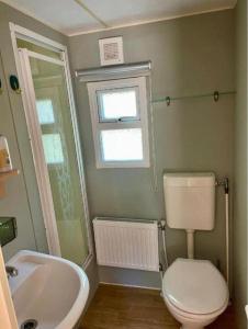 a bathroom with a toilet and a sink and a window at Prachtige stacaravan met heerlijke overkapping in Eext +69 photos
