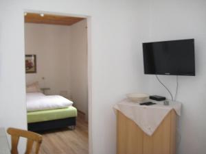 a bedroom with a bed and a flat screen tv on a wall at Pension zum Lusenblick in Mauth
