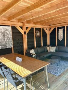 a wooden cabin with a table and a couch at Prachtige stacaravan met heerlijke overkapping in Eext