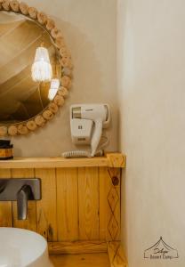 a bathroom with a mirror and a hair dryer on a counter at Dihya Luxury Camp in Merzouga +177 photos