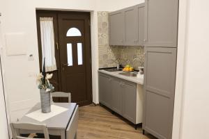 a kitchen with white cabinets and a table and a door at Le Porte sulla Costiera in Sant'Egidio del Monte Albino