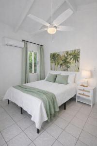 a white bedroom with a large bed and a ceiling fan at The View at Green Cay - Full AC - Walk to the Beach in Christiansted