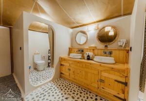 a bathroom with a sink and a toilet and mirrors at Dihya Luxury Camp in Merzouga