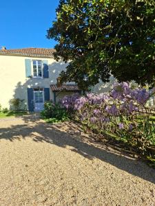 a house with purple flowers in front of a fence at La Glycine, Maison au calme avec jardin, Fibre Wi-Fi, 20 min des plages, Parking privé in Luçon