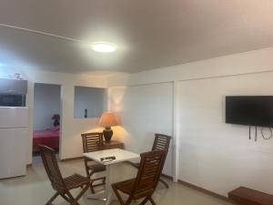 a living room with a table and chairs and a television at APPARTEMENT AMARYLLIS à 3 min de la PLAGE Pointe Marin in Sainte-Anne