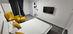 a room with a couch and a tv and yellow chairs at Kadenca in Umag