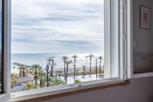 a window with a view of the ocean and palm trees at Logis Mar I Sol - Hôtel Restaurant en bord de Mer in Saint-Cyprien