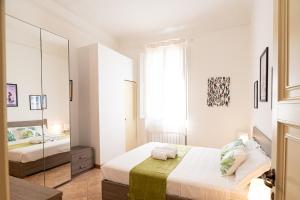 a white bedroom with a bed and a mirror at Titina Apartment Novoli Close to Center & Airport in Florence +5 photos