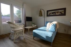 a bedroom with a bed and a chair and a window at Tussen duin en dijk in Warmenhuizen
