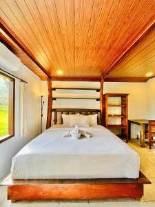 a bedroom with a large bed with a wooden ceiling at Sawit House by Natural View in Karangasem