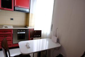 a small kitchen with a white table and red cabinets at Sea View Family Apartment Durres in Durrës