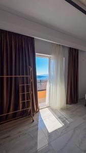 a room with a large window with a bed and a curtain at Thea Rooms in Himare