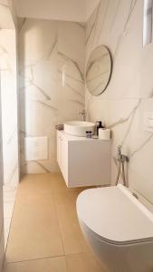 a white bathroom with a sink and a toilet at Thea Rooms in Himare