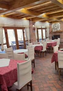 a dining room with tables and white chairs and a clock at Guesthouse Alberti Llogara in Shalë