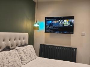 a bedroom with a bed and a tv on the wall at Studio 3 - Stylish apartment central to hospital and racecourse in Cheltenham