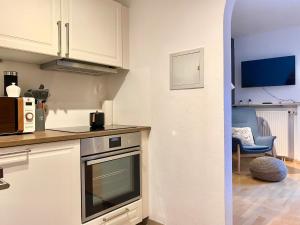 a kitchen with a stove top oven next to a living room at Seeuferresidenz am Adrian Stoop NEU eingerichtet in Bad Wiessee