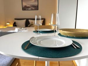 a table with a plate and two wine glasses on it at Seeuferresidenz am Adrian Stoop NEU eingerichtet in Bad Wiessee +11 photos
