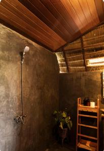 a shower in a room with a wooden ceiling at Umajro - Cabin in Karangasem