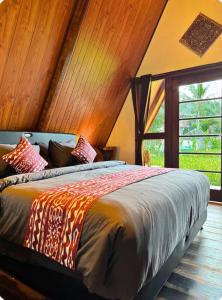 a bedroom with a bed in a room with a window at Umajro - Cabin in Karangasem