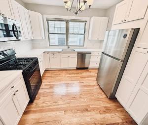 a kitchen with white cabinets and a stainless steel refrigerator at spacious room with great amenities in Boston
