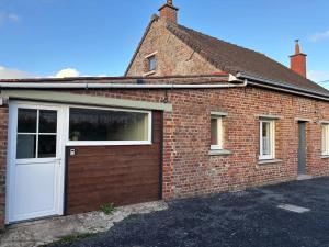 a red brick house with a white garage door at Maison rénovée - 2 chambres - 4 pers - L'Abeel Escapade in Bailleul