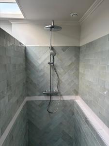 a shower with a hose in a bathroom with gray tiles at Maison rénovée - 2 chambres - 4 pers - L'Abeel Escapade in Bailleul