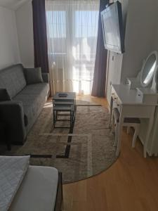 a living room with a couch and a desk and a television at Vila Vlasina in Vlasina Rid