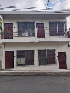 a white building with barred windows and a balcony at Zacatecoluca House 2 in Zacatecoluca +1 photo
