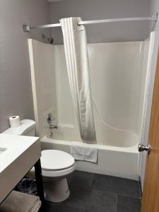 a white bathroom with a toilet and a shower at Super 8 by Wyndham Burlington in Burlington +16 photos