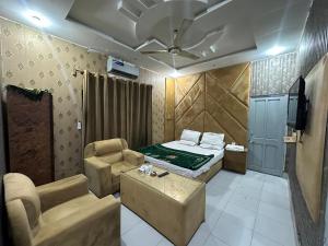 a bedroom with a bed and a couch and a tv at Hotel Sereena residence in Multan