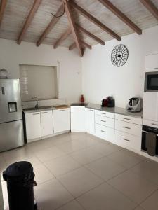 a kitchen with white cabinets and a clock on the wall at La jolie Villa in Le Lamentin