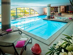 a swimming pool in a hotel room with chairs and a pool at Parc Beaumont Hôtel & Spa Pau - MGallery Collection in Pau