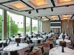 a banquet hall with white tables and chairs and windows at Pullman Melbourne Albert Park in Melbourne